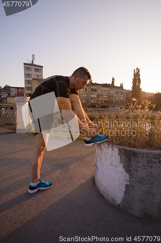 Image of man tying running shoes laces