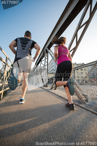 Image of young couple jogging across the bridge in the city