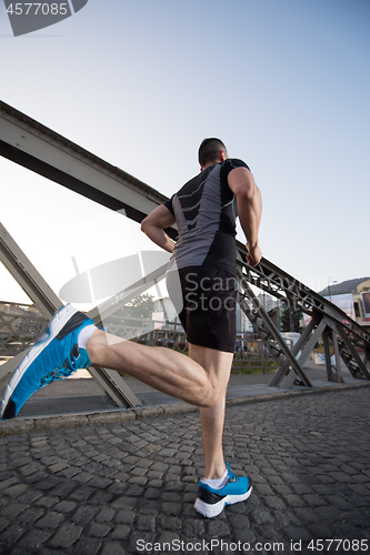 Image of man jogging across the bridge at sunny morning