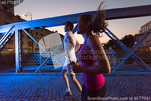 Image of couple jogging across the bridge in the city