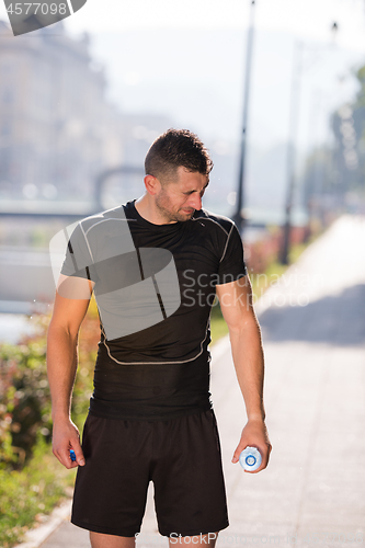 Image of man pouring water from bottle on his head