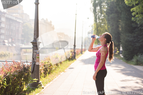 Image of woman drinking water from a bottle after jogging