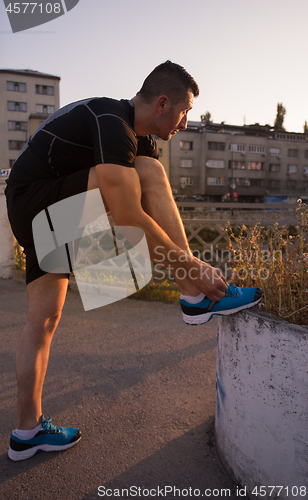 Image of man tying running shoes laces