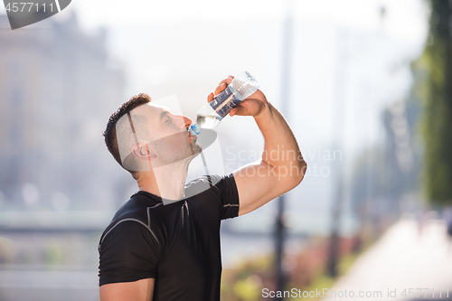 Image of man drinking water from a bottle after jogging
