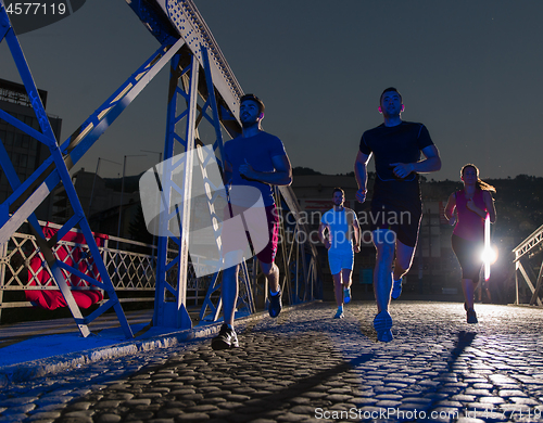 Image of young people jogging across the bridge