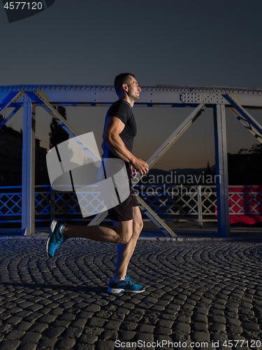 Image of man jogging across the bridge in the city