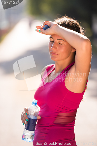 Image of woman drinking water from a bottle after jogging