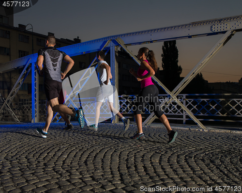 Image of young people jogging across the bridge