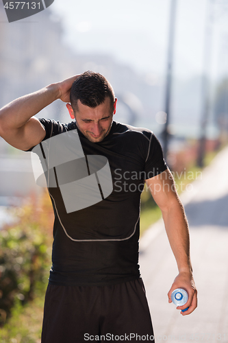 Image of man pouring water from bottle on his head