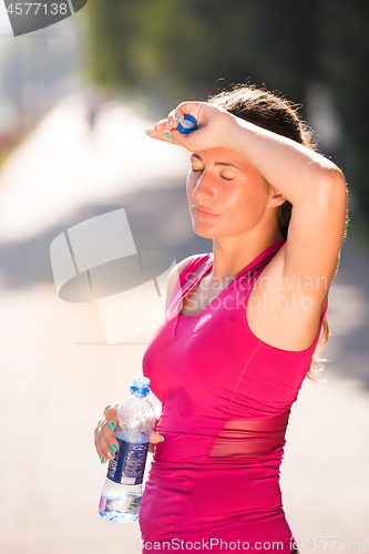 Image of woman drinking water from a bottle after jogging