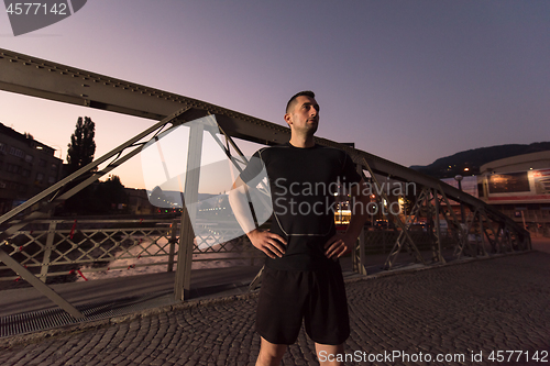 Image of man jogging across the bridge in the city