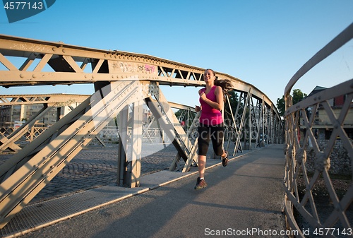 Image of woman jogging across the bridge at sunny morning