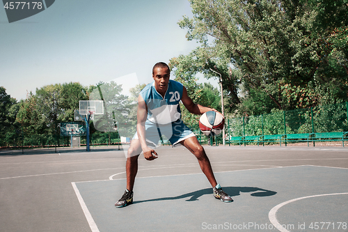 Image of Picture of young confused african basketball player practicing