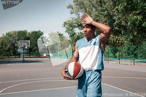 Image of Picture of young confused african basketball player practicing