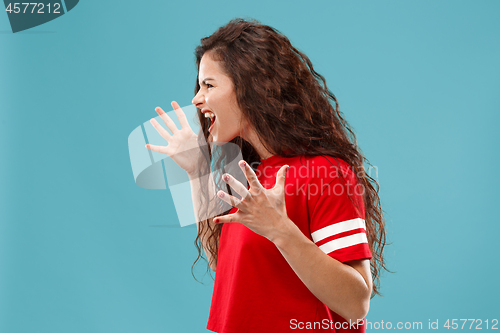 Image of The young emotional angry woman screaming on blue studio background