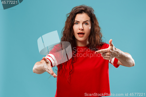 Image of Beautiful female half-length portrait isolated on blue studio backgroud. The young emotional surprised woman