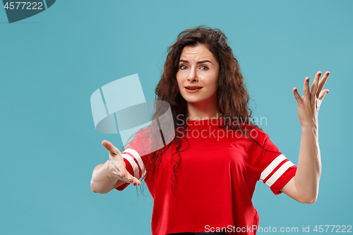 Image of Beautiful female half-length portrait isolated on blue studio backgroud. The young emotional surprised woman
