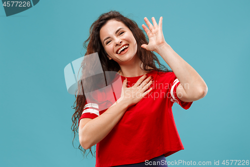 Image of Beautiful female half-length portrait isolated on blue studio backgroud. The young emotional surprised woman