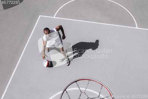 Image of Picture of young confused african basketball player practicing