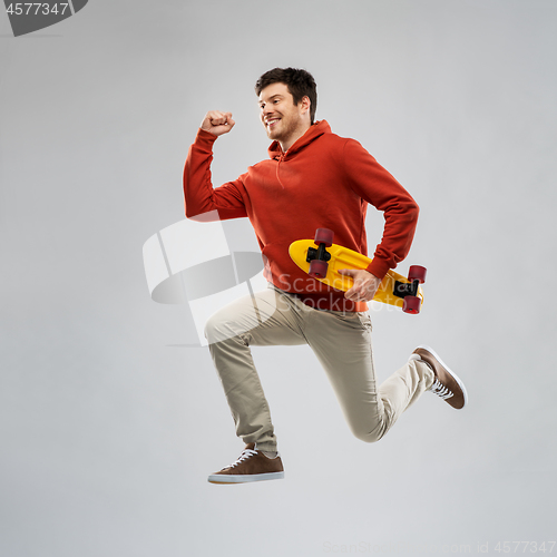 Image of smiling young man in hoodie with short skateboard