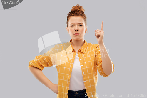 Image of red haired teenage girl pointing finger up