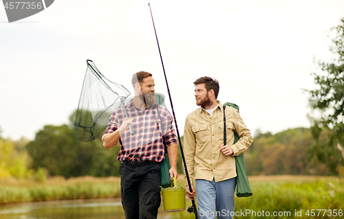 Image of friends with fishing rods and net at lake or river