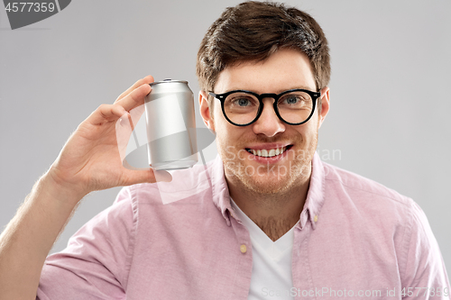 Image of happy young man holding tin can with soda