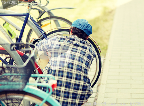 Image of man fastening bicycle lock on street parking