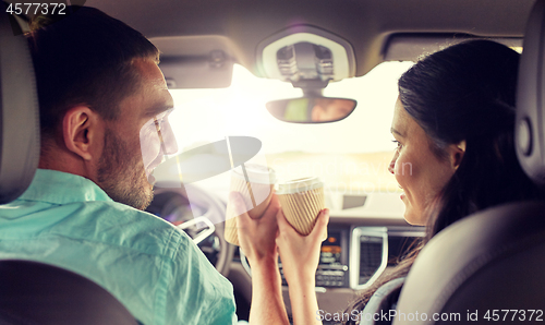 Image of happy man and woman driving in car with coffee