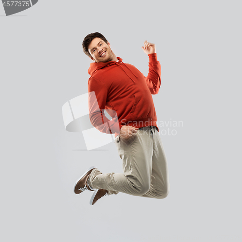 Image of young man in hoodie jumping over grey background