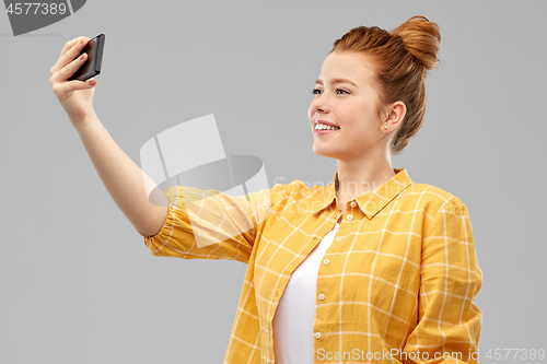 Image of redhead teenage girl taking selfie by smartphone