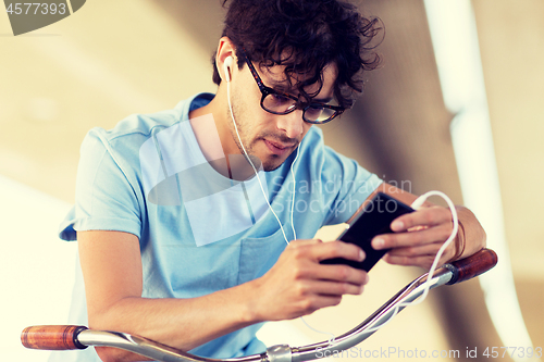 Image of man with smartphone and earphones on bicycle