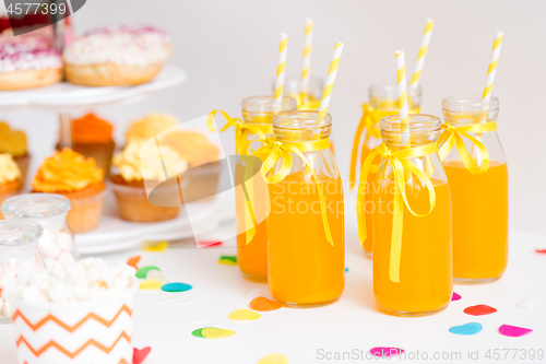 Image of orange juice in glass bottles with paper straws