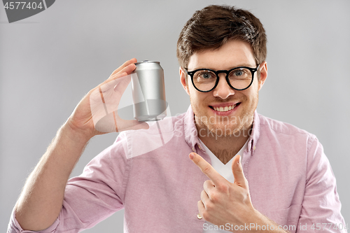 Image of happy young man holding tin can with soda