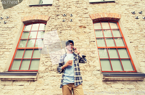 Image of man with smartphone drinking coffee on city street