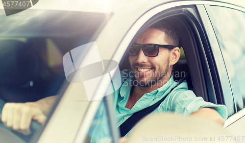 Image of happy smiling man in sunglasses driving car