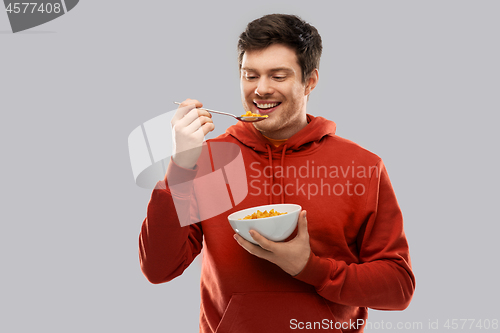 Image of smiling young man in red hoodie eating cereals