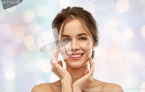 Image of smiling young woman touching her face