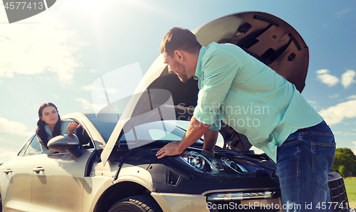 Image of couple with open hood of broken car at countryside