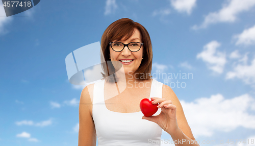 Image of portrait of smiling senior woman holding red heart