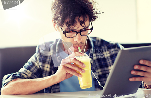 Image of man with tablet pc and earphones sitting at cafe