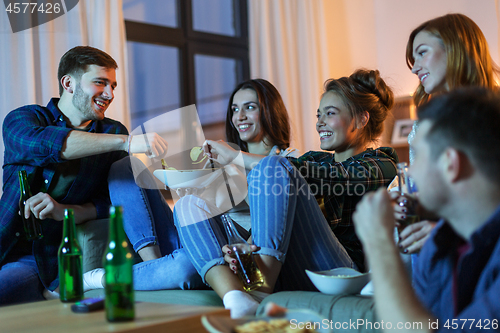 Image of friends with drinks and snacks watching tv at home