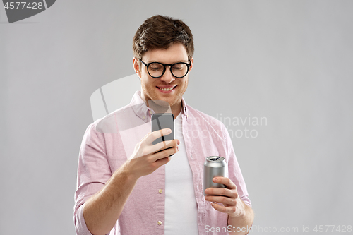 Image of young man in glasses with smartphone and drink