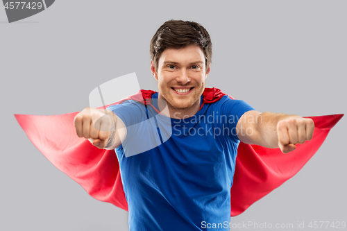 Image of man in red superhero cape over grey background