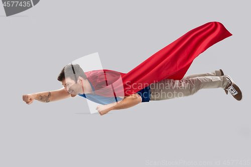 Image of man in red superhero cape flying in air