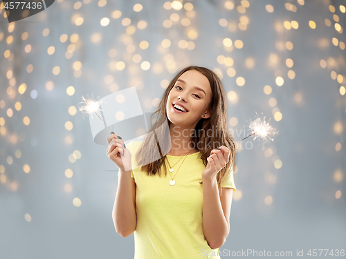 Image of happy teenage girl with two sparklers over lights