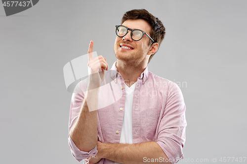 Image of smiling young man in glasses pointing finger up