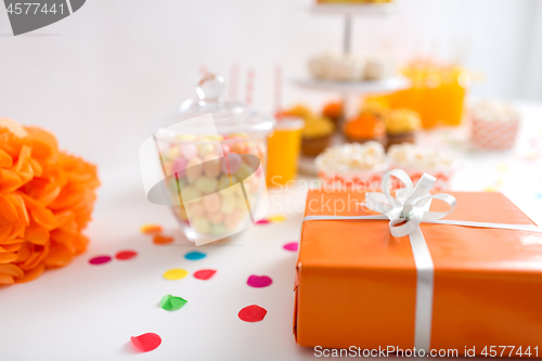 Image of birthday present in orange wrap on table at party