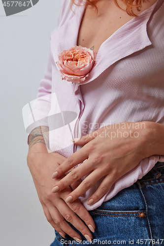 Image of Sexual red-haired girl with fresh flower living coral color in hands with tattoo 