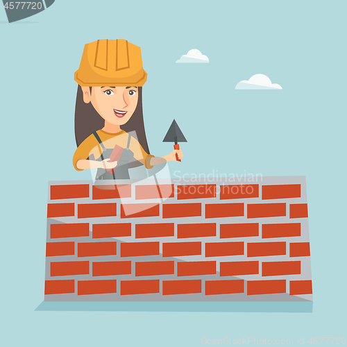 Image of Young caucasian bricklayer building a brick wall.